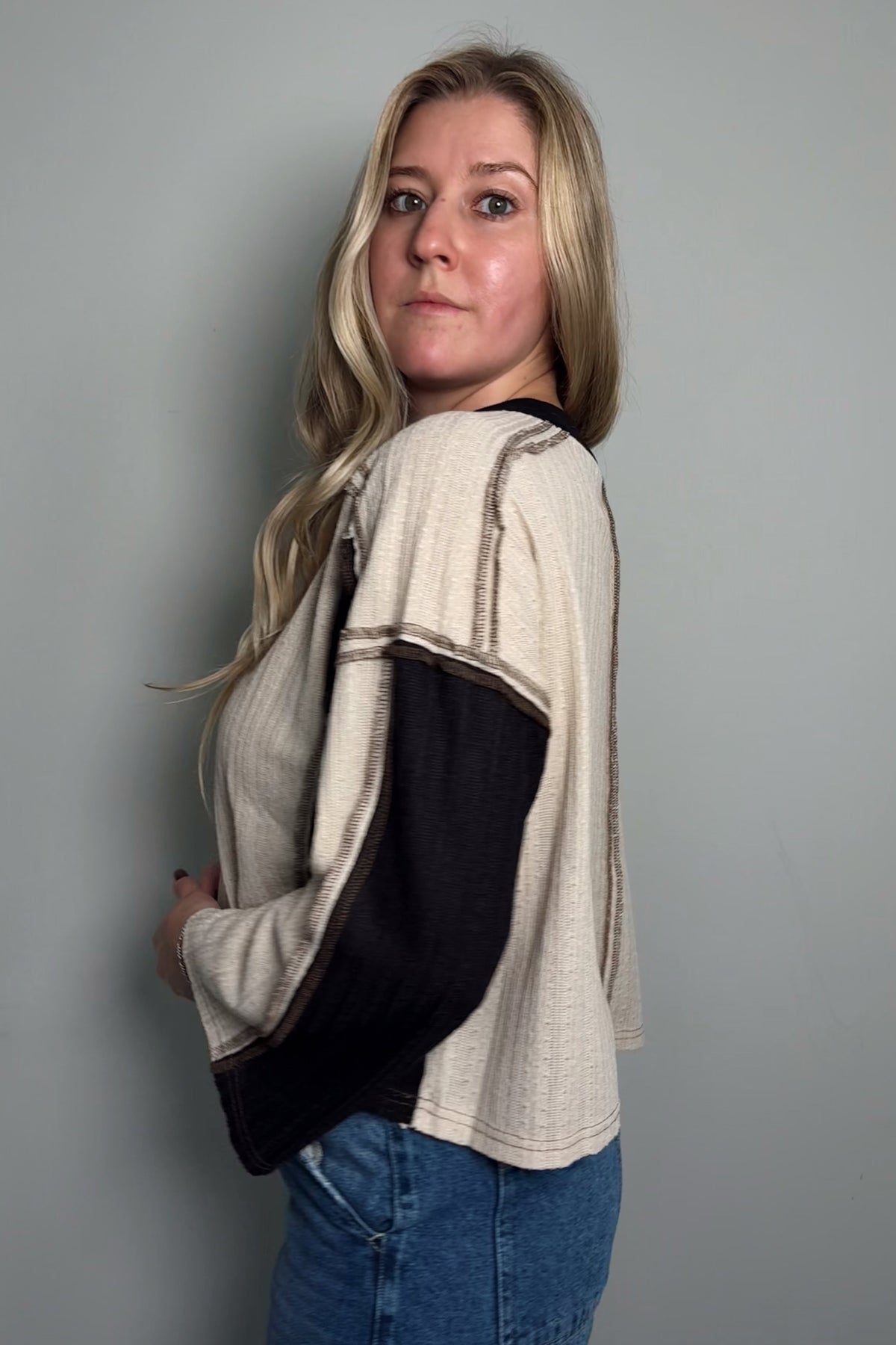 Back view of the Sawyer colorblock knit top showing the exposed raglan sleeve seams and black back panel