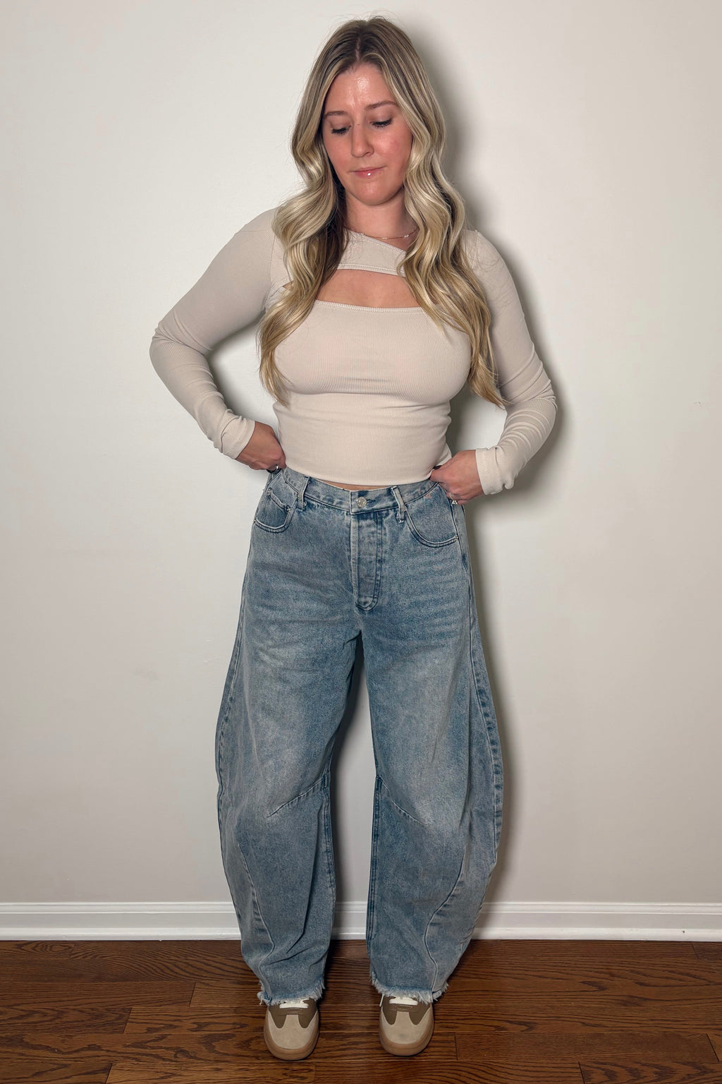 Straight-on view of Ingrid barrel jeans with hands at the waistband, showing front pockets, curved seams, and raw hems.

