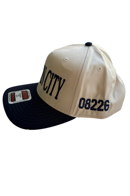 A baseball cap with a cream-colored crown and a dark navy blue brim. The crown features the word 'CITY' in dark navy lettering and the number '08226' on the side.
