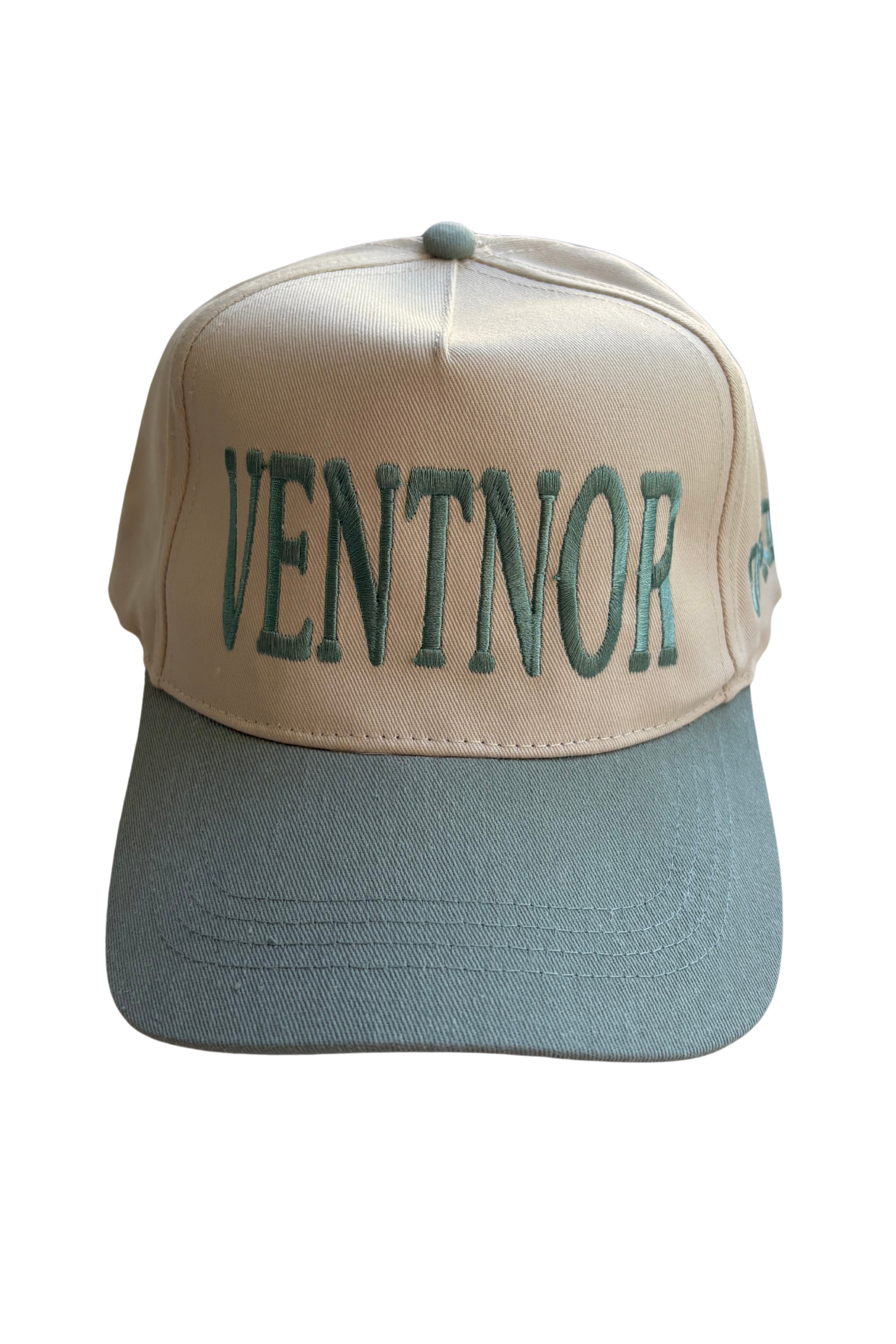 A structured baseball cap with a beige front panel and brim, featuring the word 'VENTNOR' embroidered in dark green across the front. The side panels and curved brim are a muted sage green, and a small green logo is visible on the side.