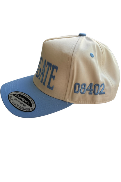 A beige and blue snapback cap with 'GATE' and '08402' embroidered in blue on the front panels and visor, shown on a plain white background.
