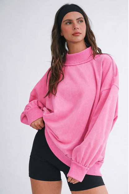 Woman wearing a pink oversized sweatshirt and black shorts on a white background