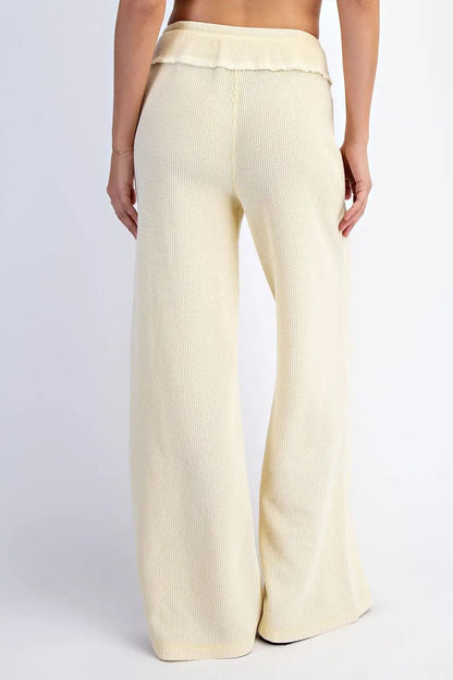 Cream-colored wide-leg pants worn by a person on a white background