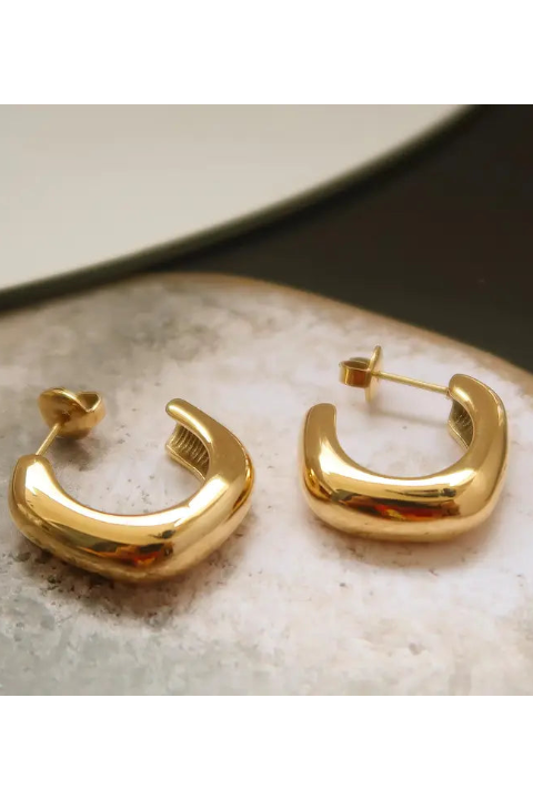 Gold hoop earrings on a textured surface