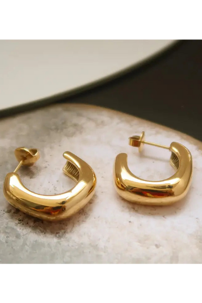 Gold hoop earrings on a textured surface