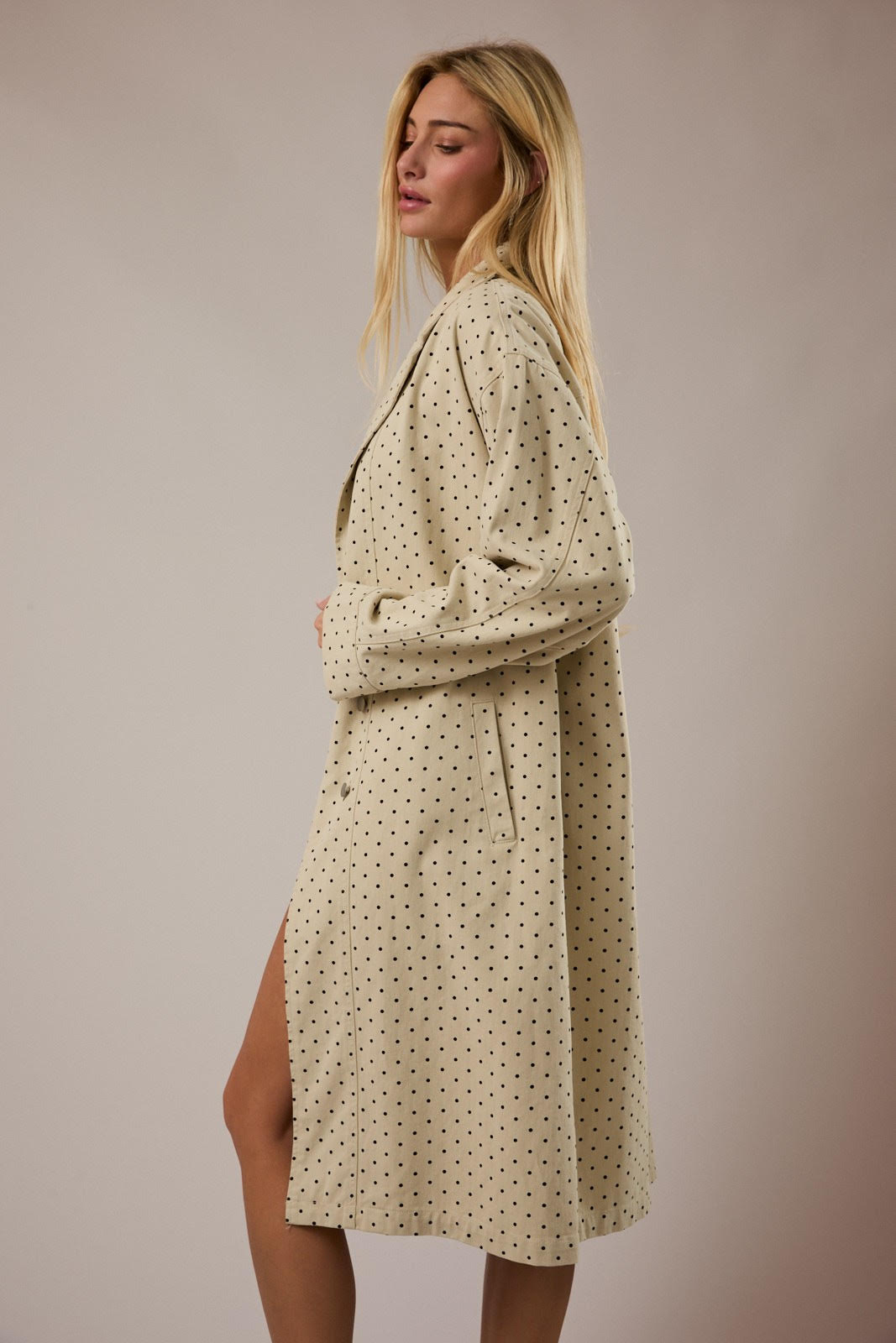 Woman wearing a beige polka dot jacket against a plain background